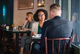 interview, black woman in interview, two people by window, lady on phone, in a coffee shot